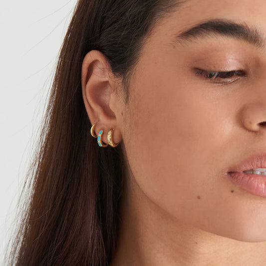 Close-up of a person wearing gold hoop earrings with a white background