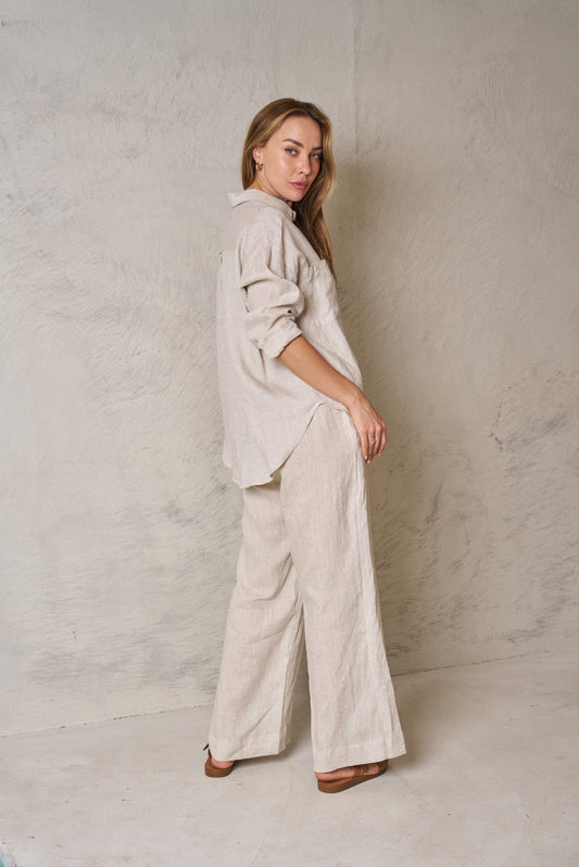Woman wearing a beige outfit against a plain wall